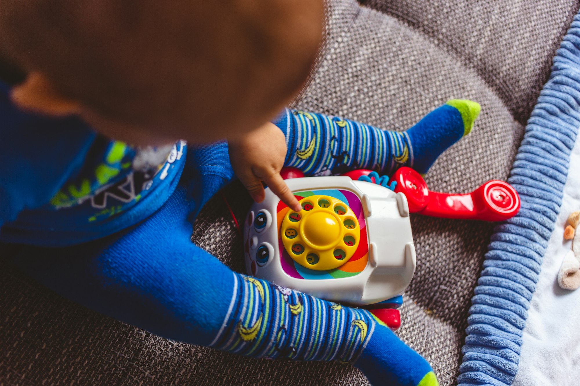 Cute child in blue tights for laying with a toy telephone on the couch